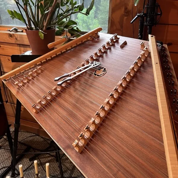 Hammered dulcimer in a log cabin studio, candles below